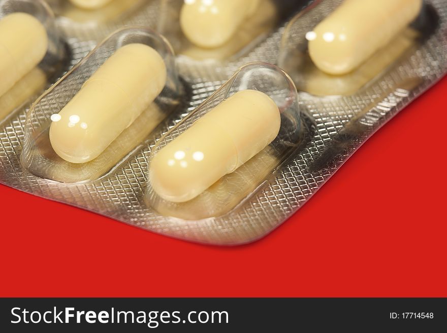 Pills in blister pack in red background, macro. Pills in blister pack in red background, macro