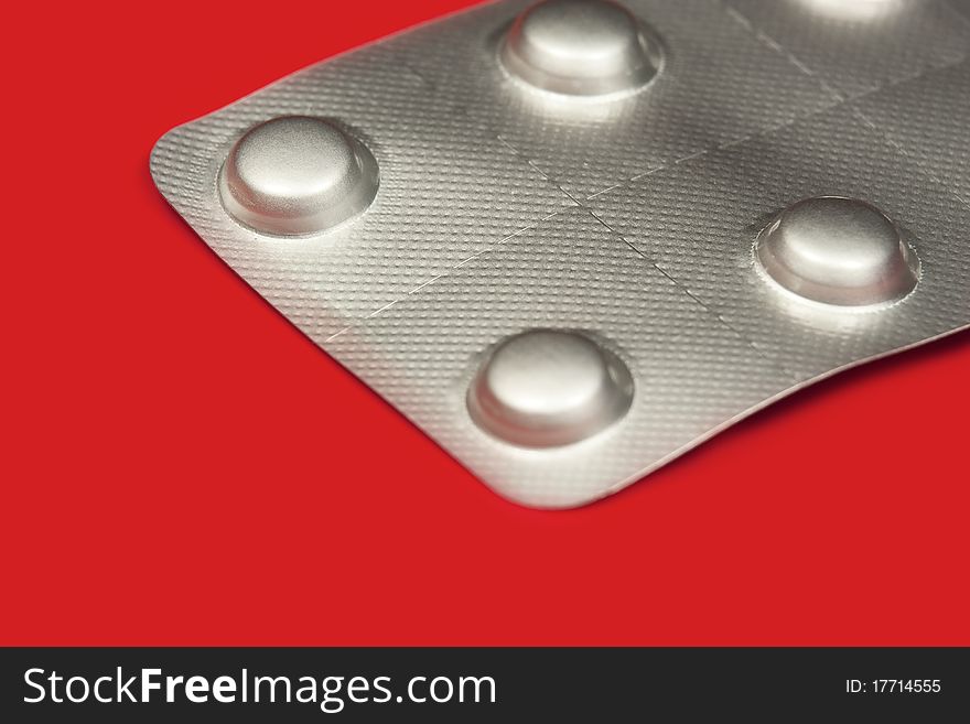 Pills in blister pack in red background, macro