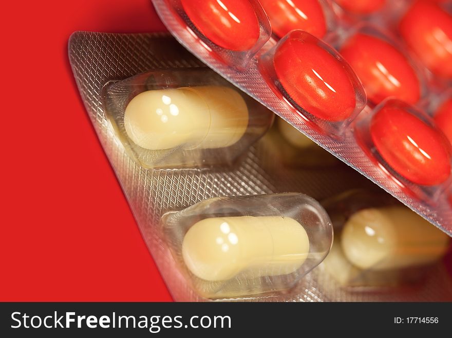 Pills in blister pack in red background, macro