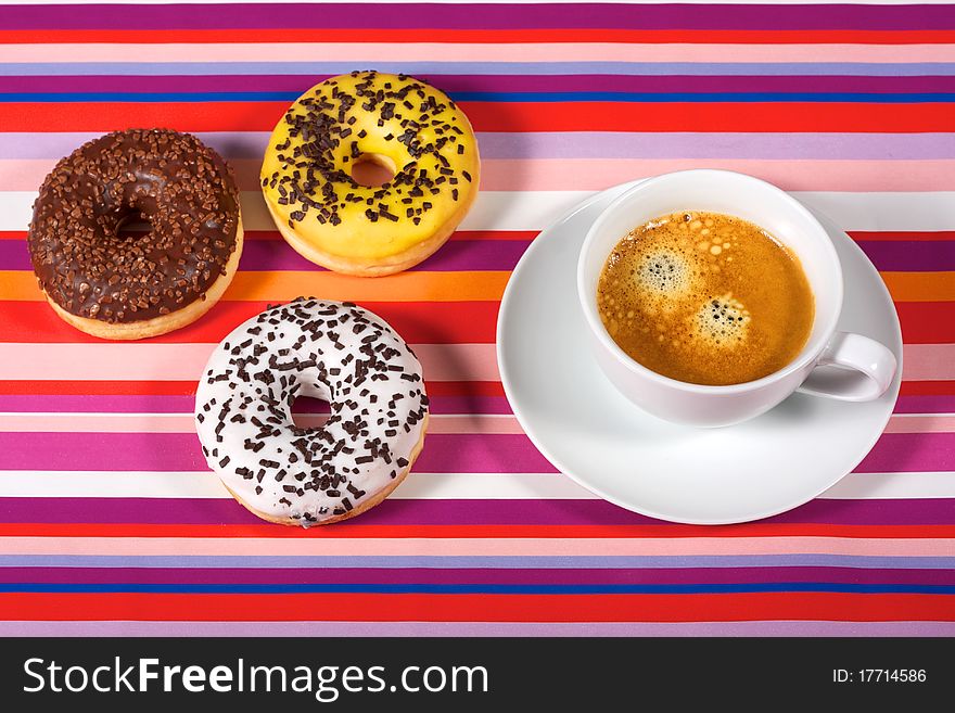 Donuts with cup of coffee on red tablecloth