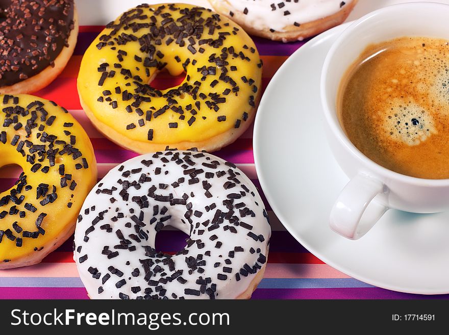 Donuts with cup of coffee on red tablecloth