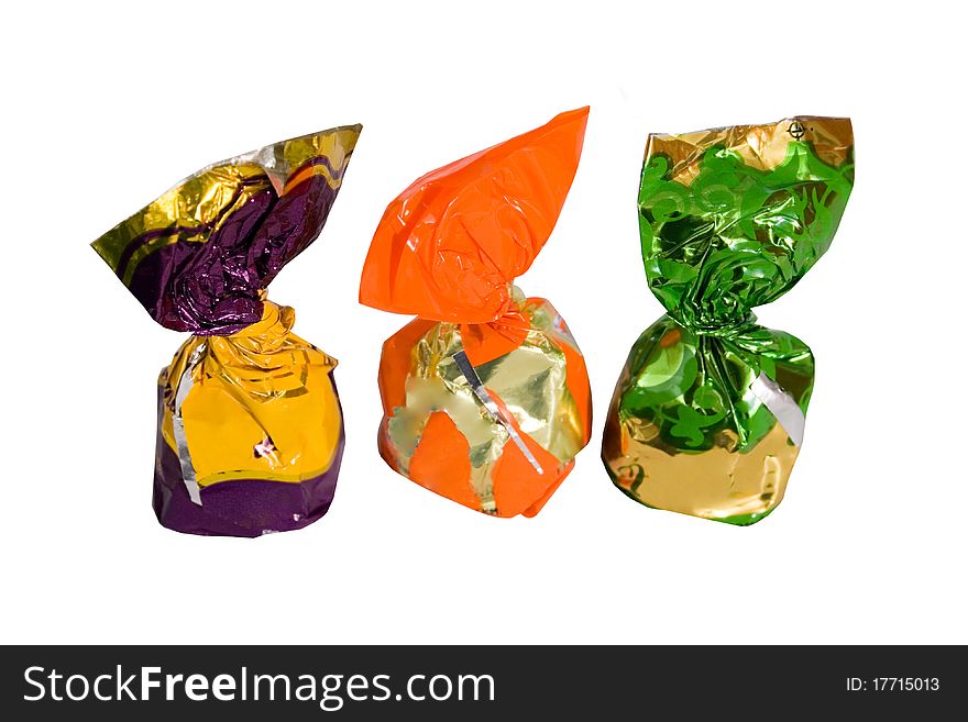 Three chocolates in a colored shiny packaging. white background. Three chocolates in a colored shiny packaging. white background.