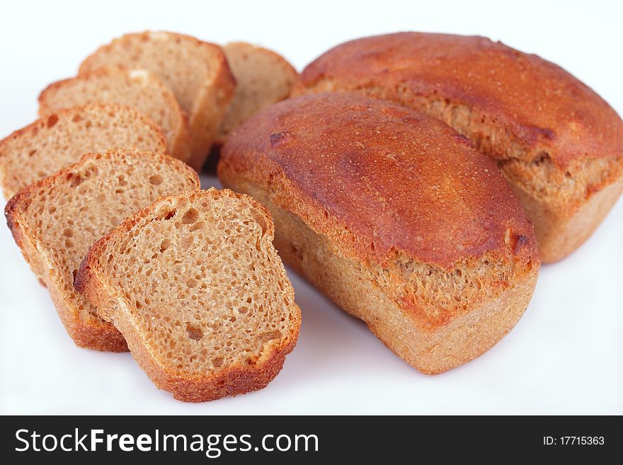 Fresh baked homemade loafs of rye bread and slices of cut rye bread isolated on white background. Fresh baked homemade loafs of rye bread and slices of cut rye bread isolated on white background