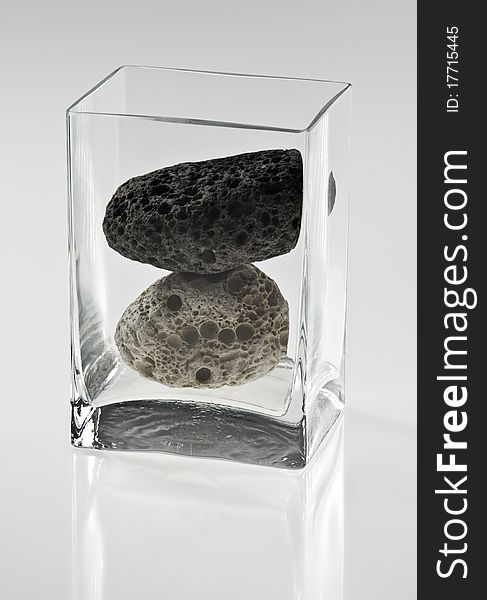 Two stones in a glass container on white background