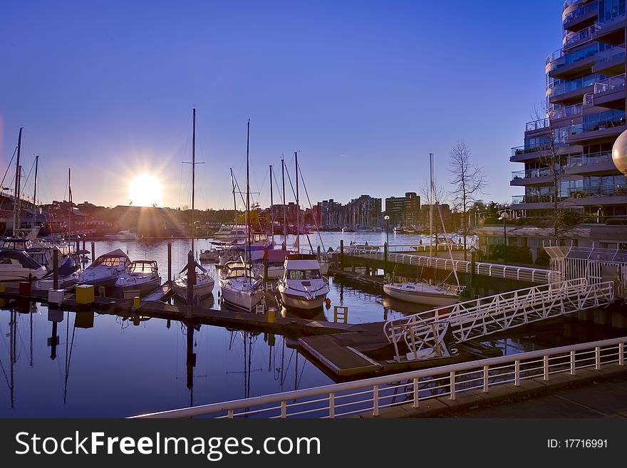 A view of sailboat in the harbor as the sun is setting in the city. A view of sailboat in the harbor as the sun is setting in the city