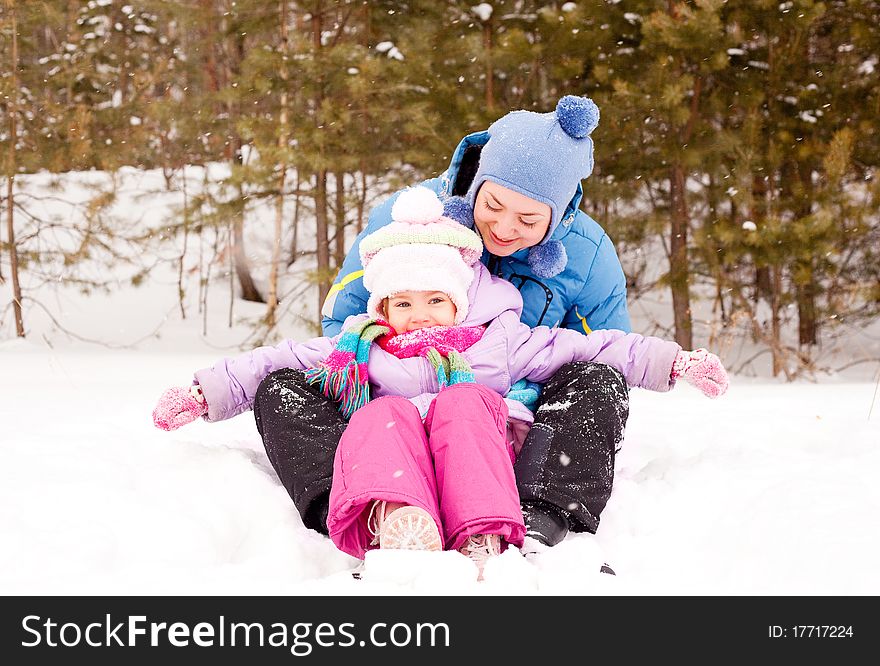 Happy family; young mother and her daughter having fun in the winter park (focus on the child). Happy family; young mother and her daughter having fun in the winter park (focus on the child)