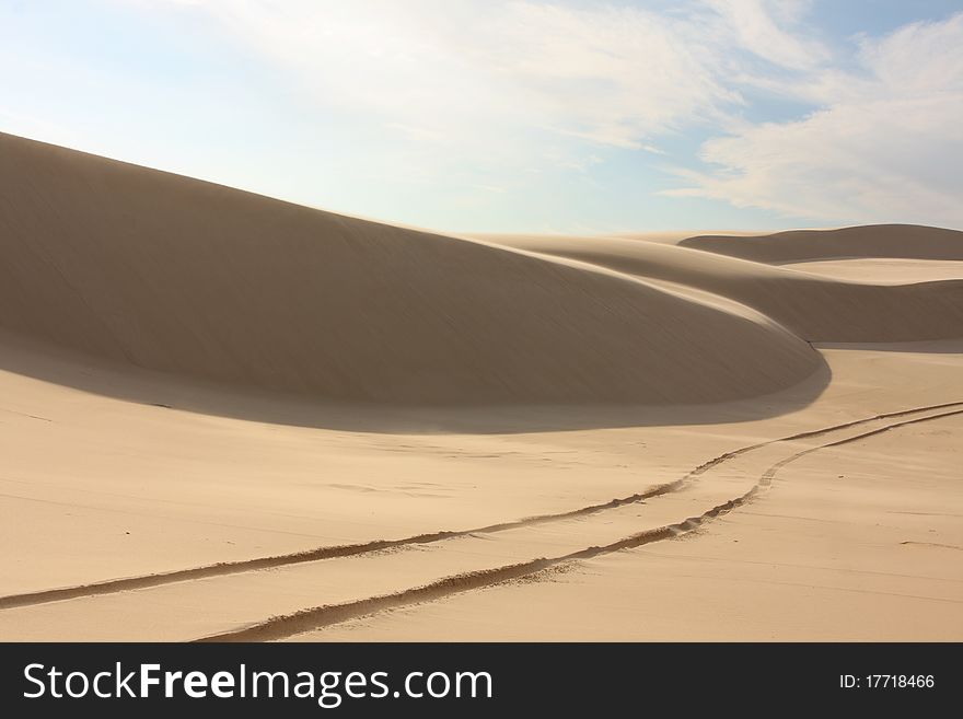 Desolate sand dunes with tyre tracks on sunny day. Desolate sand dunes with tyre tracks on sunny day