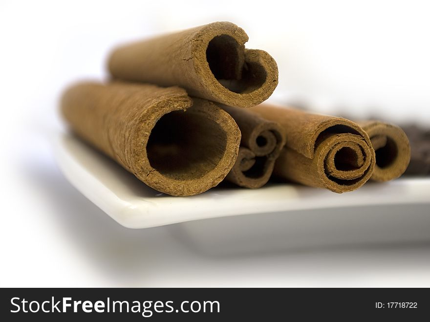 Some sticks of cinnamon lie on a white porcelain plate