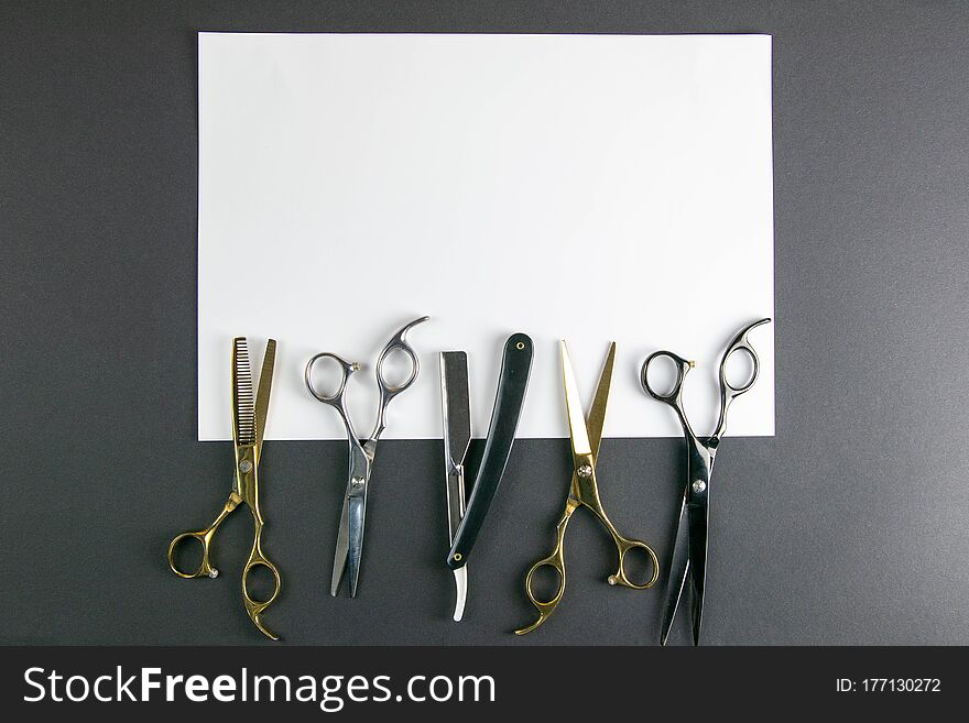 Scissors, hair clipper, combs, dangerous razor on a white sheet on black background. Hairdressing concept