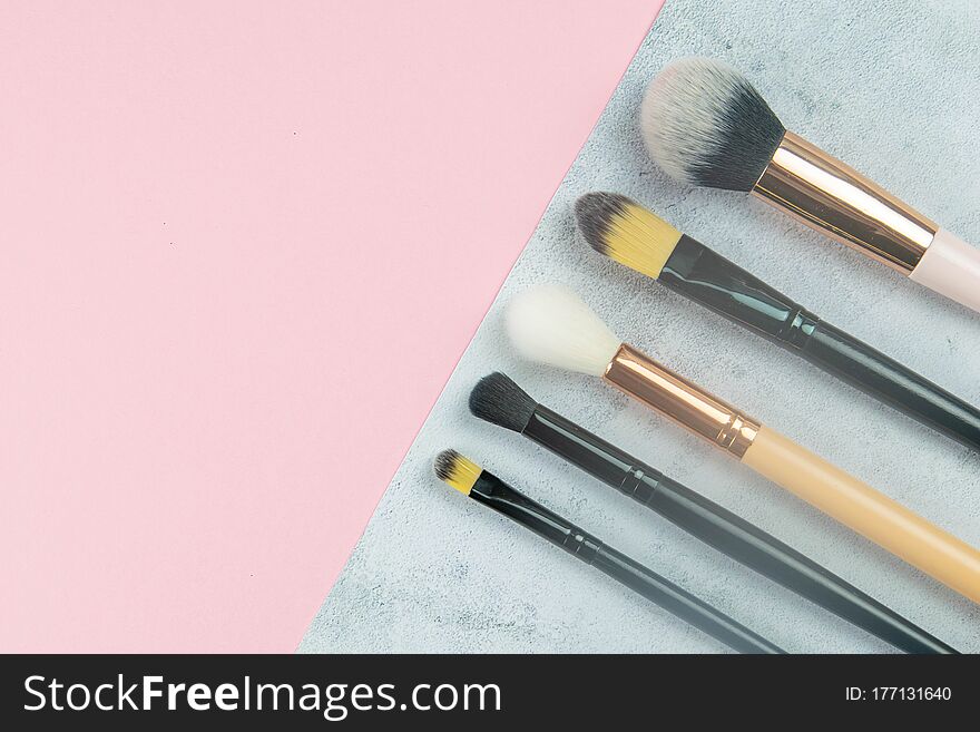 Makeup brushes stand on a concrete background that stands on a pink table