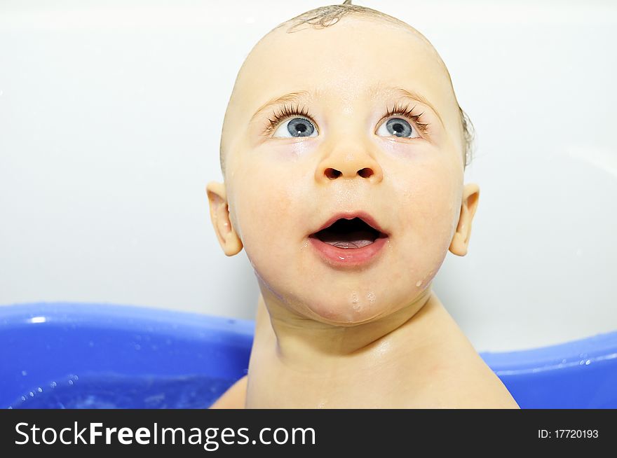 Excited blue-eyed baby boy taking a bath
