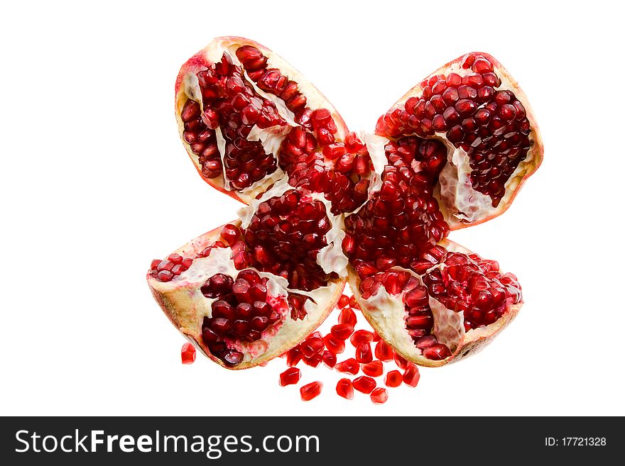 The pomegranate broken on some parts with the grains scattered nearby (on a white background). The pomegranate broken on some parts with the grains scattered nearby (on a white background)