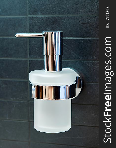 An isolated stainless steel metal and glass soap dispenser.