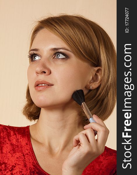 Portrait of the girl in a red with a brush for make-up. Portrait of the girl in a red with a brush for make-up