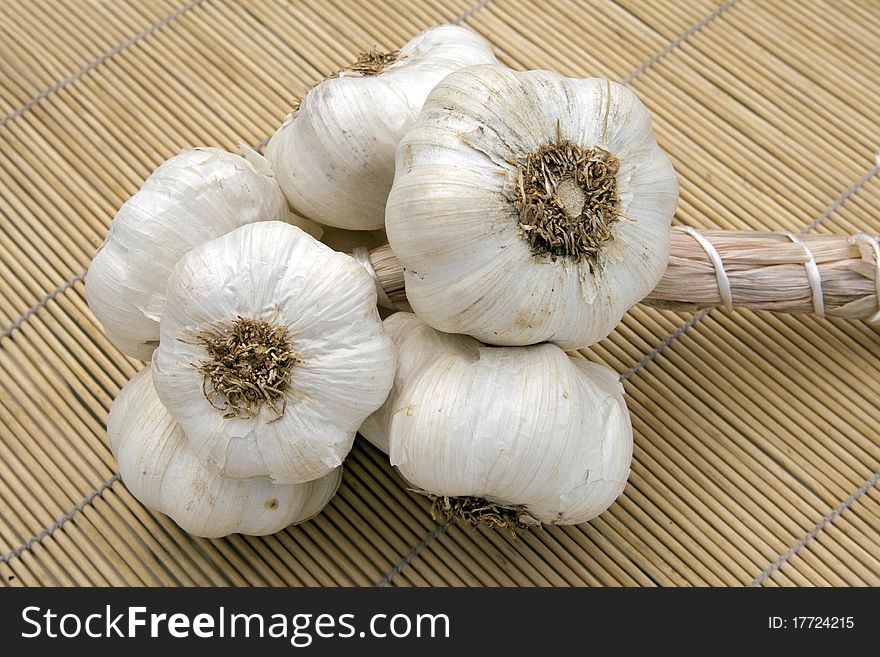 Closeup of fresh braided garlic on bamboo place-mat.