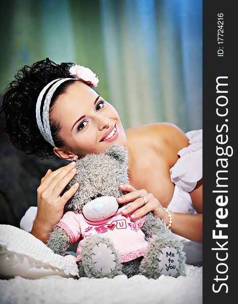 Portrait beautiful bride with teddy bear on white bed in wedding day. Portrait beautiful bride with teddy bear on white bed in wedding day