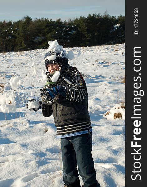Little boy with blue winter hat having fun, throwing a snowball while getting a snowball against his head. Little boy with blue winter hat having fun, throwing a snowball while getting a snowball against his head