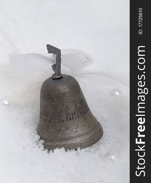 Iron christmas bell in snow with pearls and white feathers and white ribbon