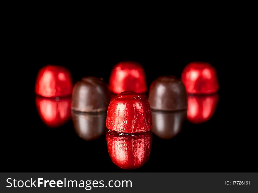 Set of sweets on redlection surface. Black background. Studio shot.