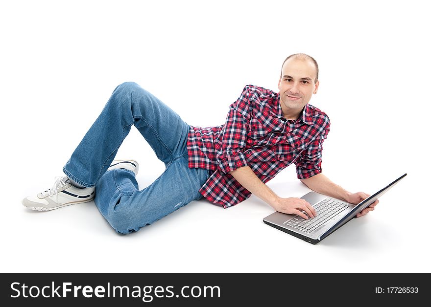 Happy young man surfing on laptop, lying down. Isolated on white background