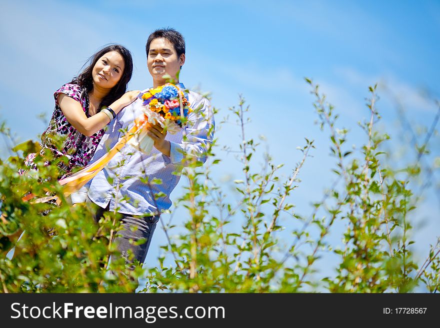 Romantic couples standing outdoors with flowers bouquet