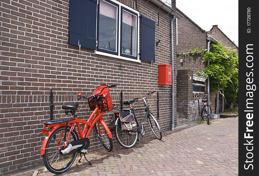 A modern red bike and a red mailbox against the wall of a old house. A modern red bike and a red mailbox against the wall of a old house