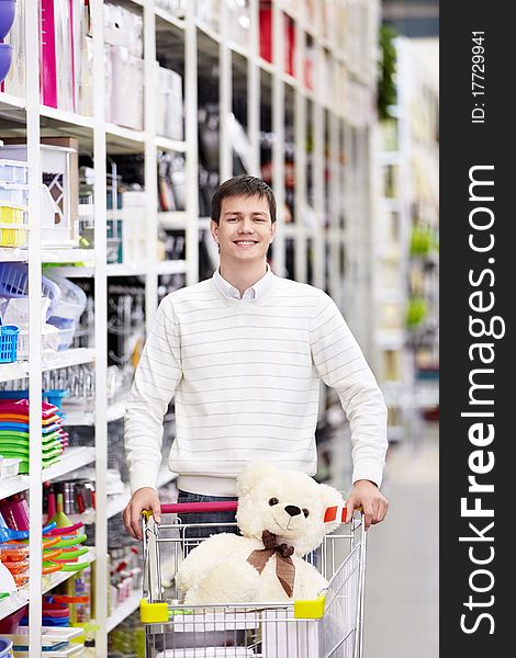 A young man with a cart in the store. A young man with a cart in the store