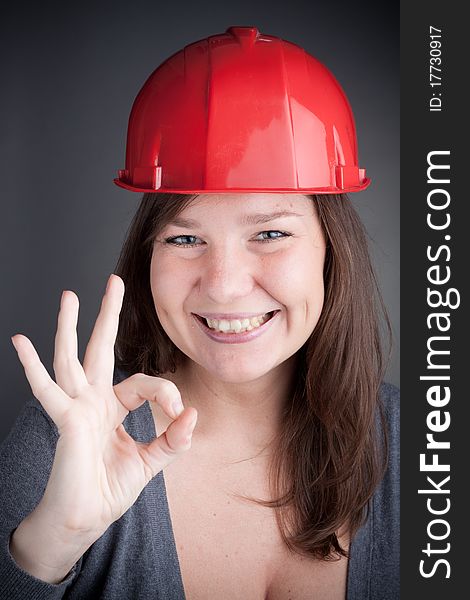 Young Engineer Woman doing the ok sign, wearing red safety hat