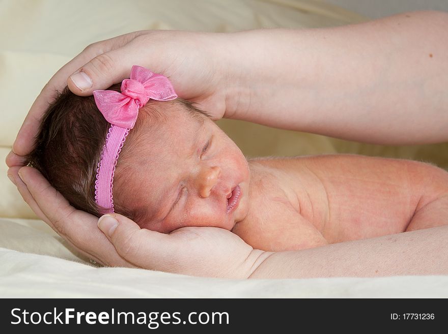A cute 1 week old baby being held in her Mom's hands. A cute 1 week old baby being held in her Mom's hands.