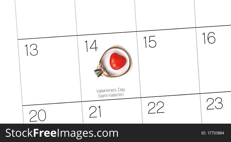 A top view of a calendar showing and a candy heart within an engagement ring marking February 14th. A top view of a calendar showing and a candy heart within an engagement ring marking February 14th.