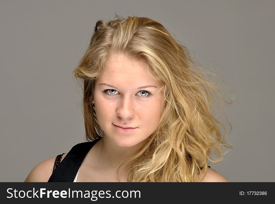Young blond close-up against gray background. Hair is slightly tousled. Young blond close-up against gray background. Hair is slightly tousled