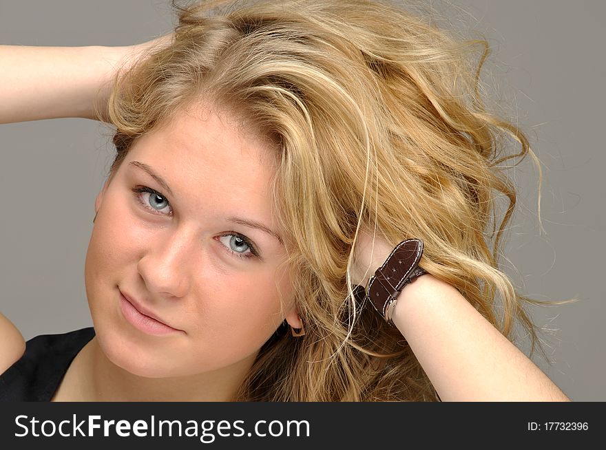 Portrait of a teen girl touching his hair. Studio shot against gray background. Portrait of a teen girl touching his hair. Studio shot against gray background