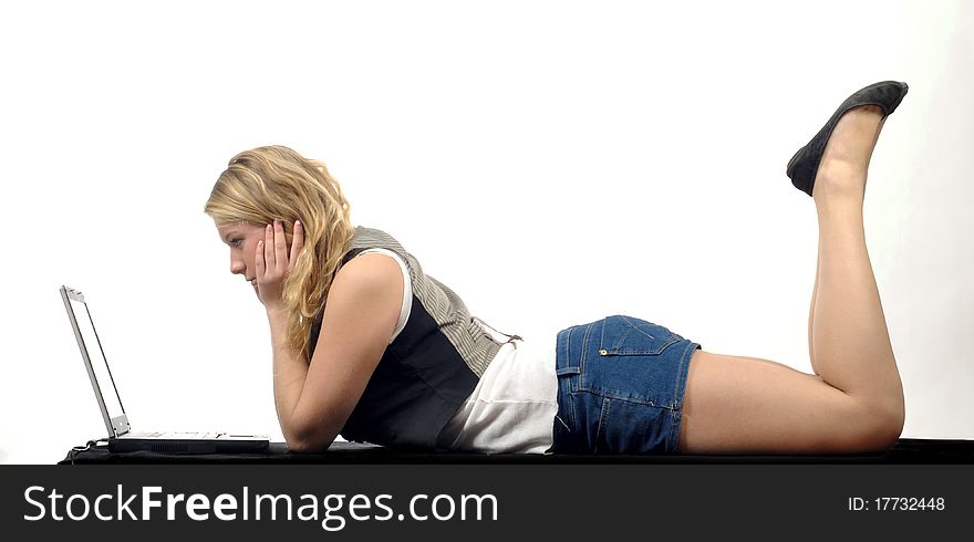 Young woman laying on black surface with laptop. Studio shot against white background. Young woman laying on black surface with laptop. Studio shot against white background