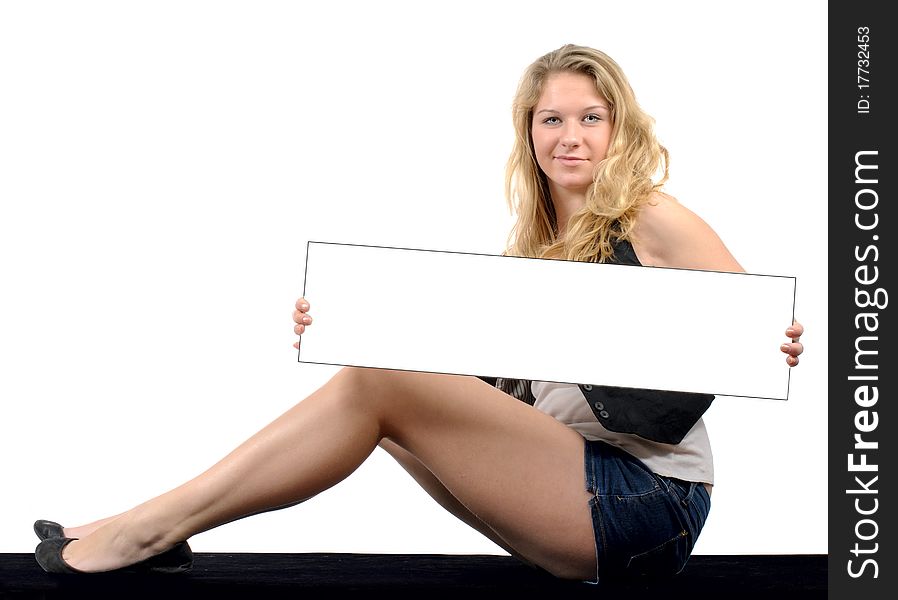 Young woman sitting on black surface against white background holding white card. Young woman sitting on black surface against white background holding white card