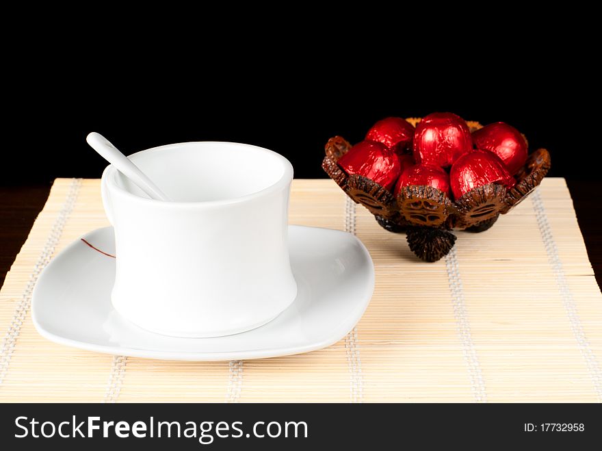 A cup with sweets on the table. Black background. Studio shot. A cup with sweets on the table. Black background. Studio shot.