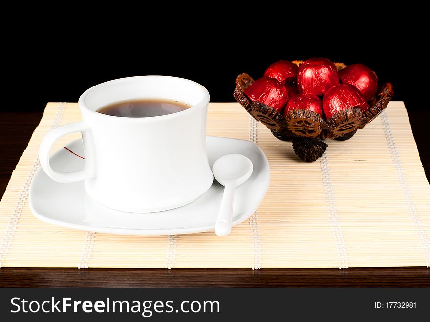 A cup of tea with sweets on the table. Black background. Studio shot. A cup of tea with sweets on the table. Black background. Studio shot.