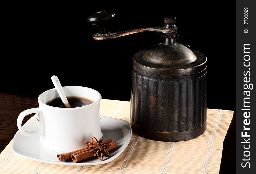 A cup of coffee with an old grinder and cinnamon. Studio shot. A cup of coffee with an old grinder and cinnamon. Studio shot.