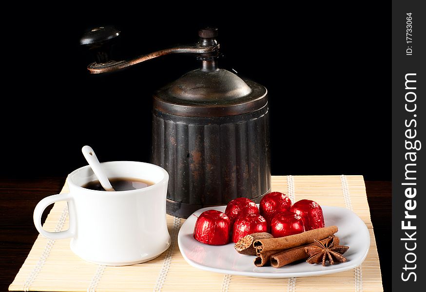 A cup of coffee with an old grinder, sweets and cinnamon. Studio shot. A cup of coffee with an old grinder, sweets and cinnamon. Studio shot.