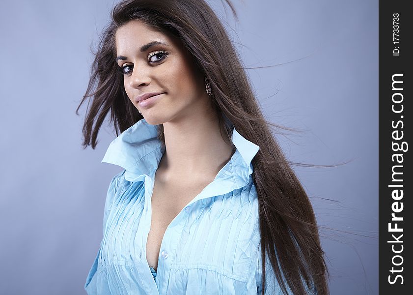 Portrait of trendy young woman in funky blue shirt pose against gray background