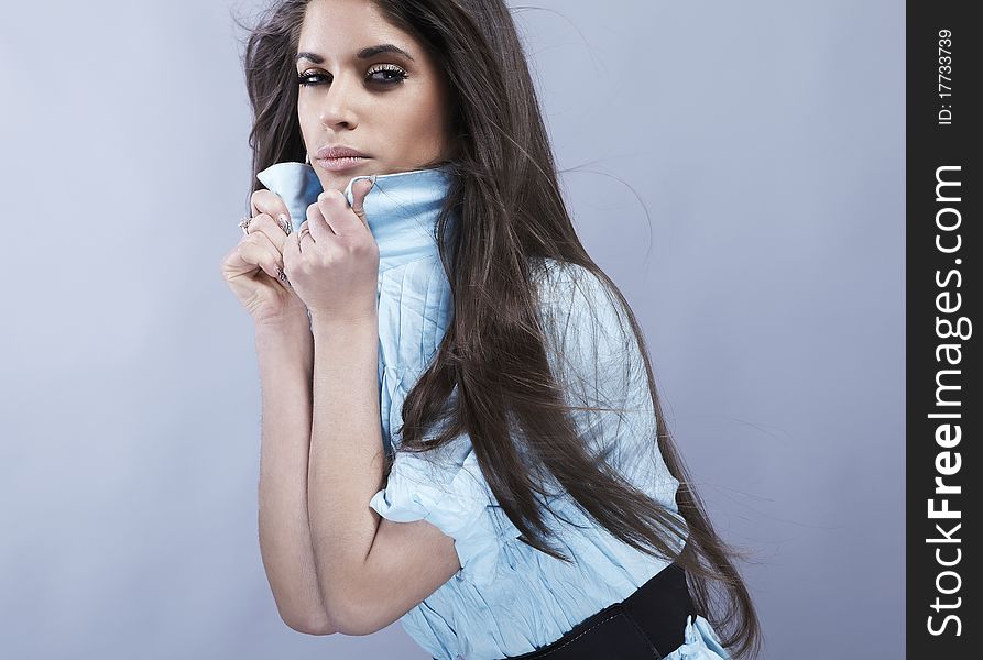 Portrait of trendy young woman in funky blue shirt pose against gray background