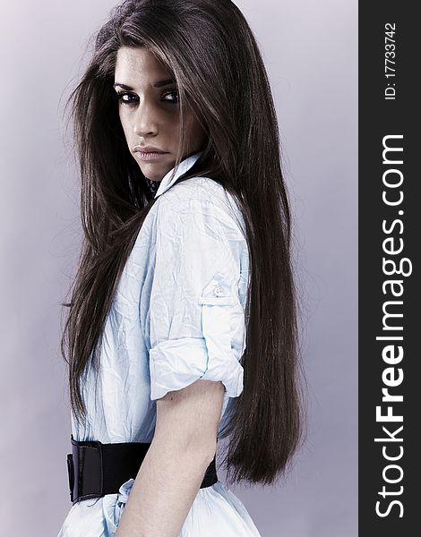 Portrait of trendy young woman in funky blue shirt pose against gray background