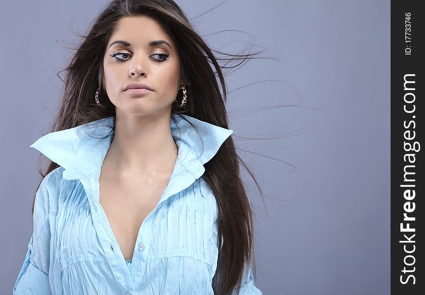 Portrait of trendy young woman in funky blue shirt pose against gray background