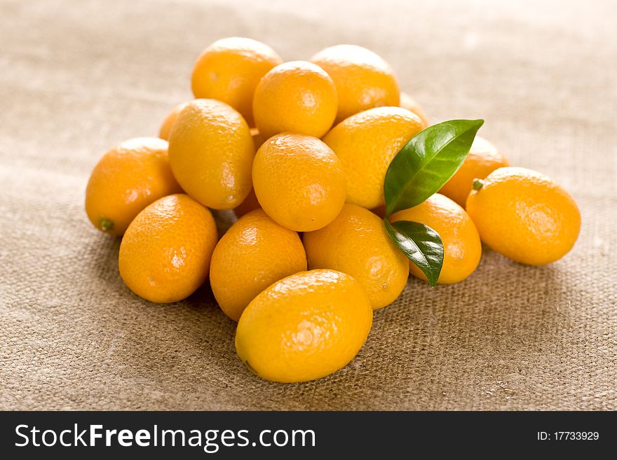 Kumquat small orange fruits on brown background