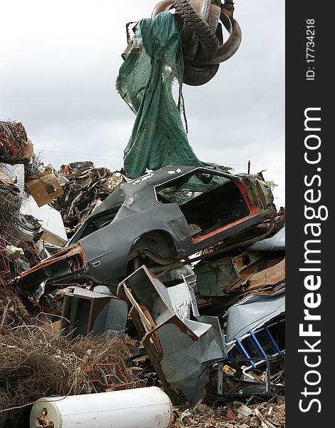 An old car is dropped by a grappling crane at the crushing yard. An old car is dropped by a grappling crane at the crushing yard.