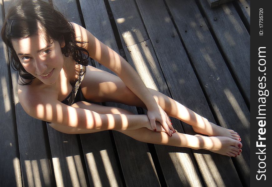 Girl in swimsuit sitting on wooden slats. Girl in swimsuit sitting on wooden slats