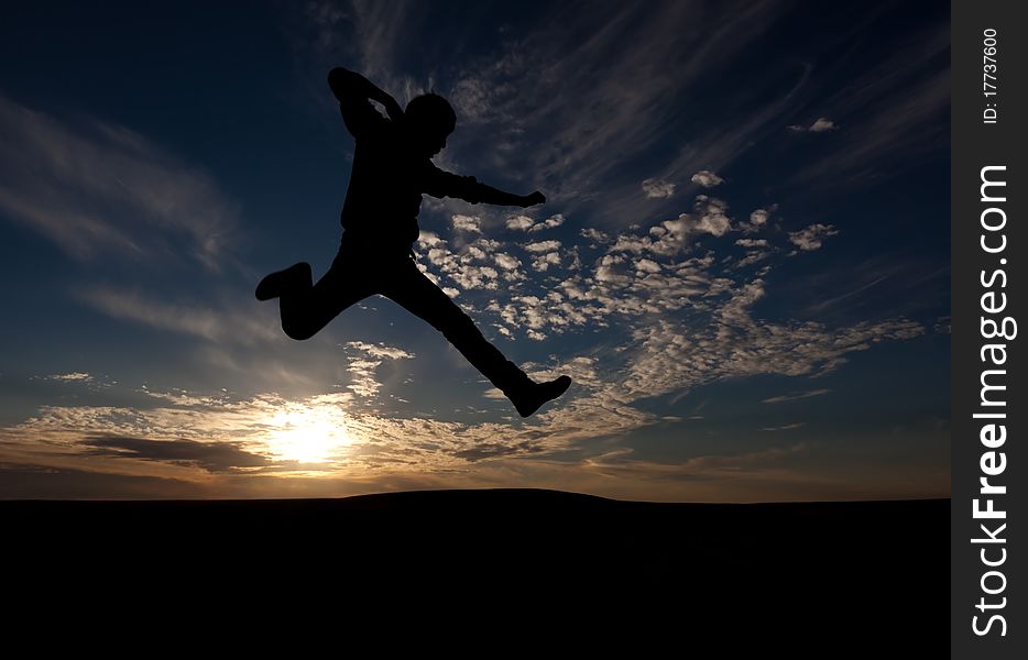 The silhouette of the guy against a decline, the beautiful sky, jumps upwards, a kick. The silhouette of the guy against a decline, the beautiful sky, jumps upwards, a kick