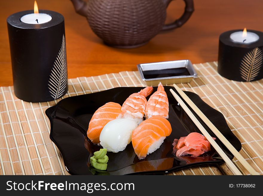 Tasty dish of assorted sushi on black plate and teapot. Tasty dish of assorted sushi on black plate and teapot