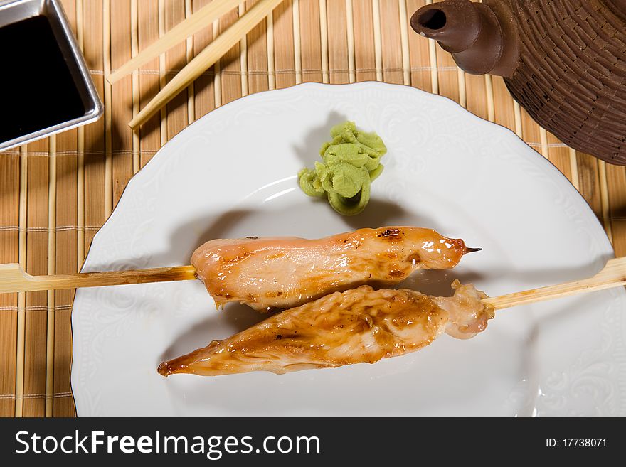 Hot barbecued chicken fillet  as closeup on a white plate