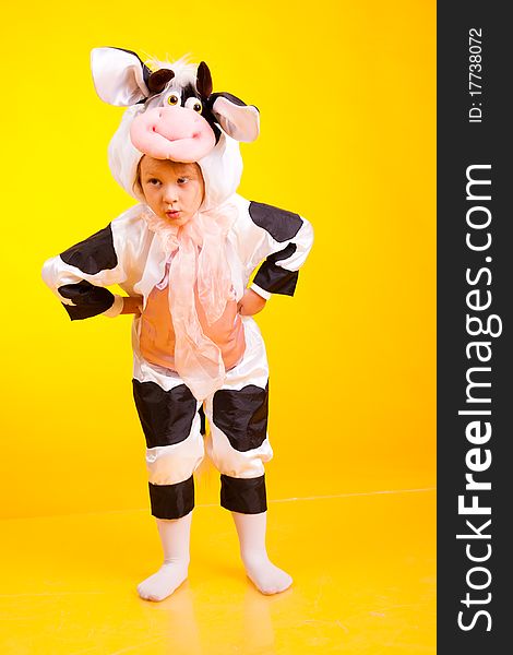 Little girl in the suit of cow on a yellow background