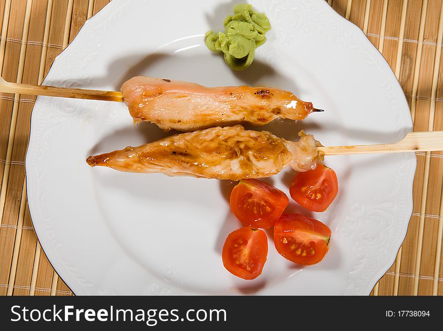 Hot barbecued chicken fillet as closeup on a white plate